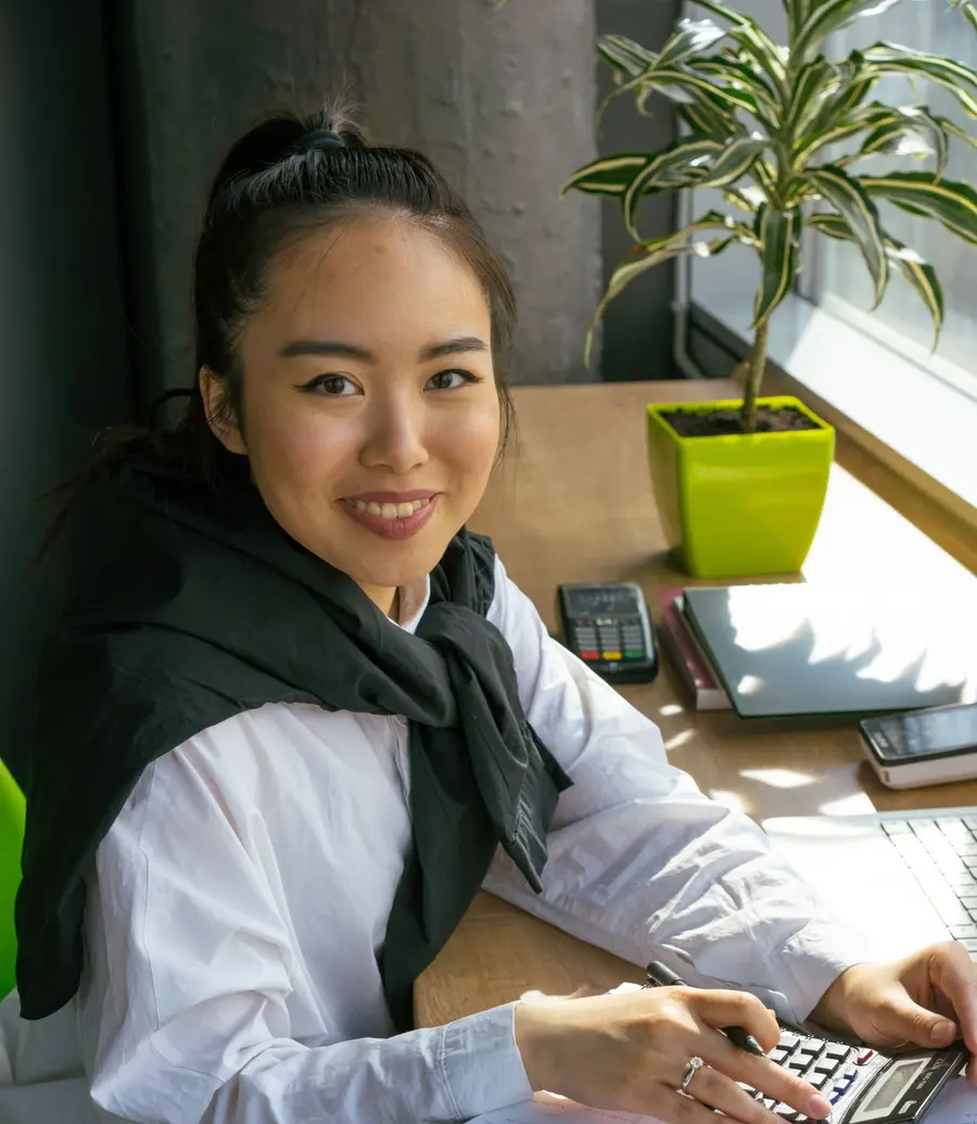 Accountant working with a calculator and laptop in a bright office