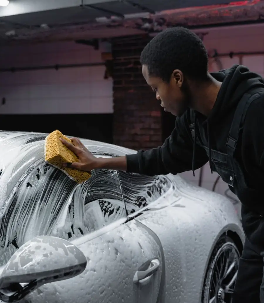 Young man washing a luxury car with a soapy sponge