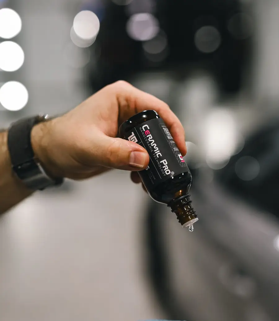 Detailer applying ceramic coating to a car panel with a blue applicator