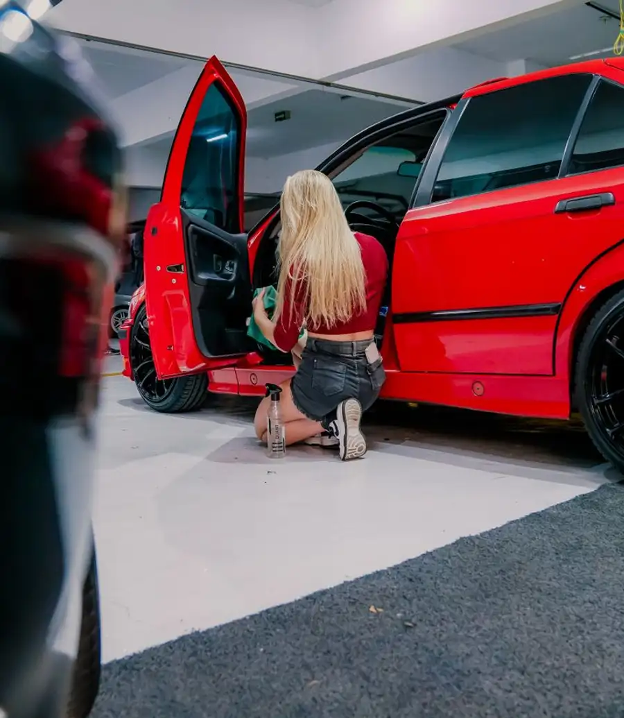 Detailer cleaning the interior of a car with a microfibre cloth