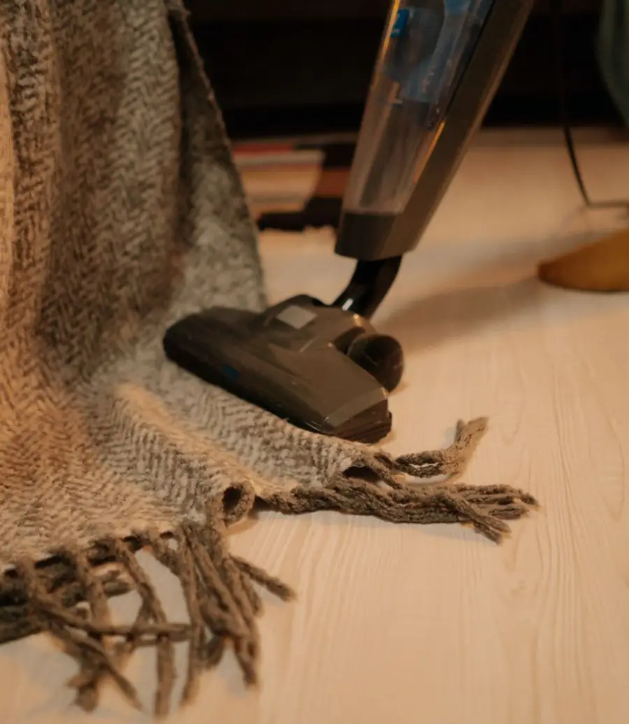 A stick vacuum cleaning a wool throw in warm evening light