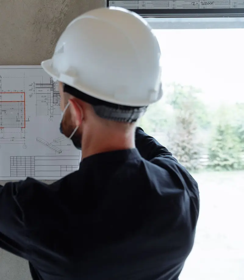 Contractor reviewing a blueprint against a concrete column