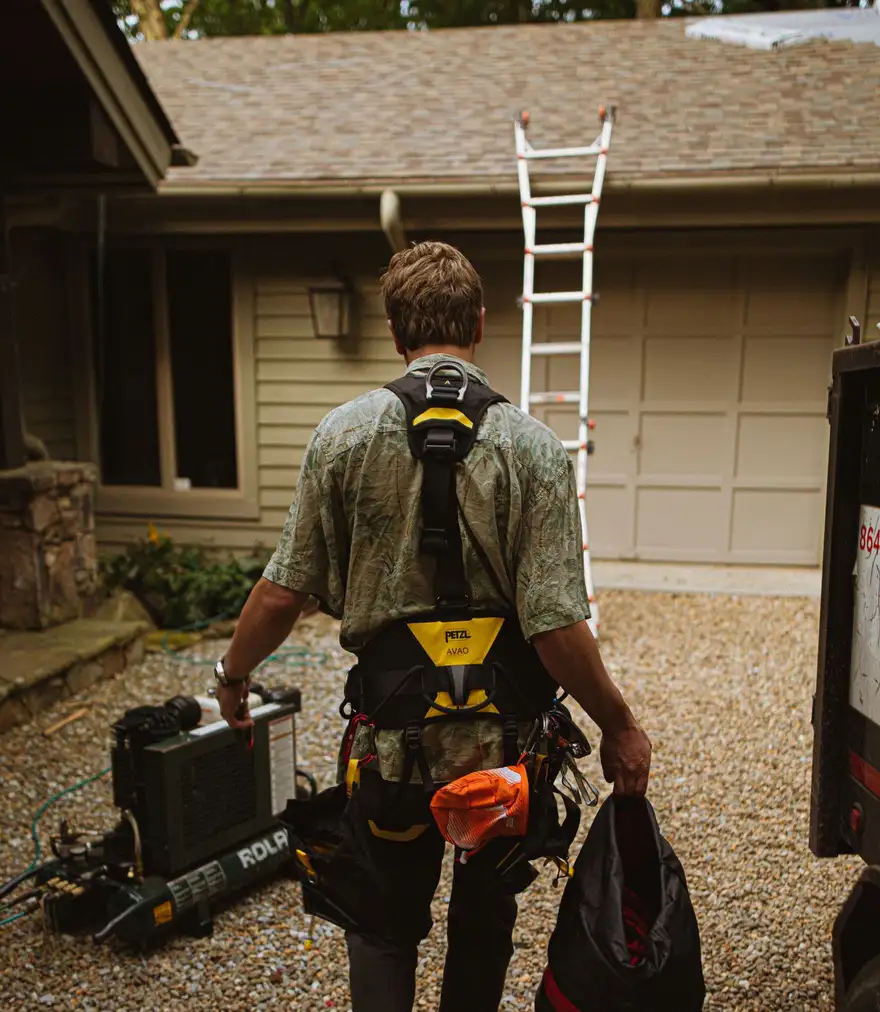 Roofer with a ladder set up against the side of a house