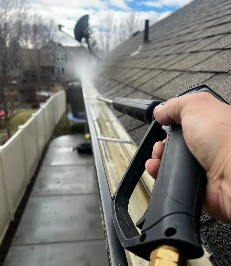 Residential gutter being cleaned along the edge of a roofline