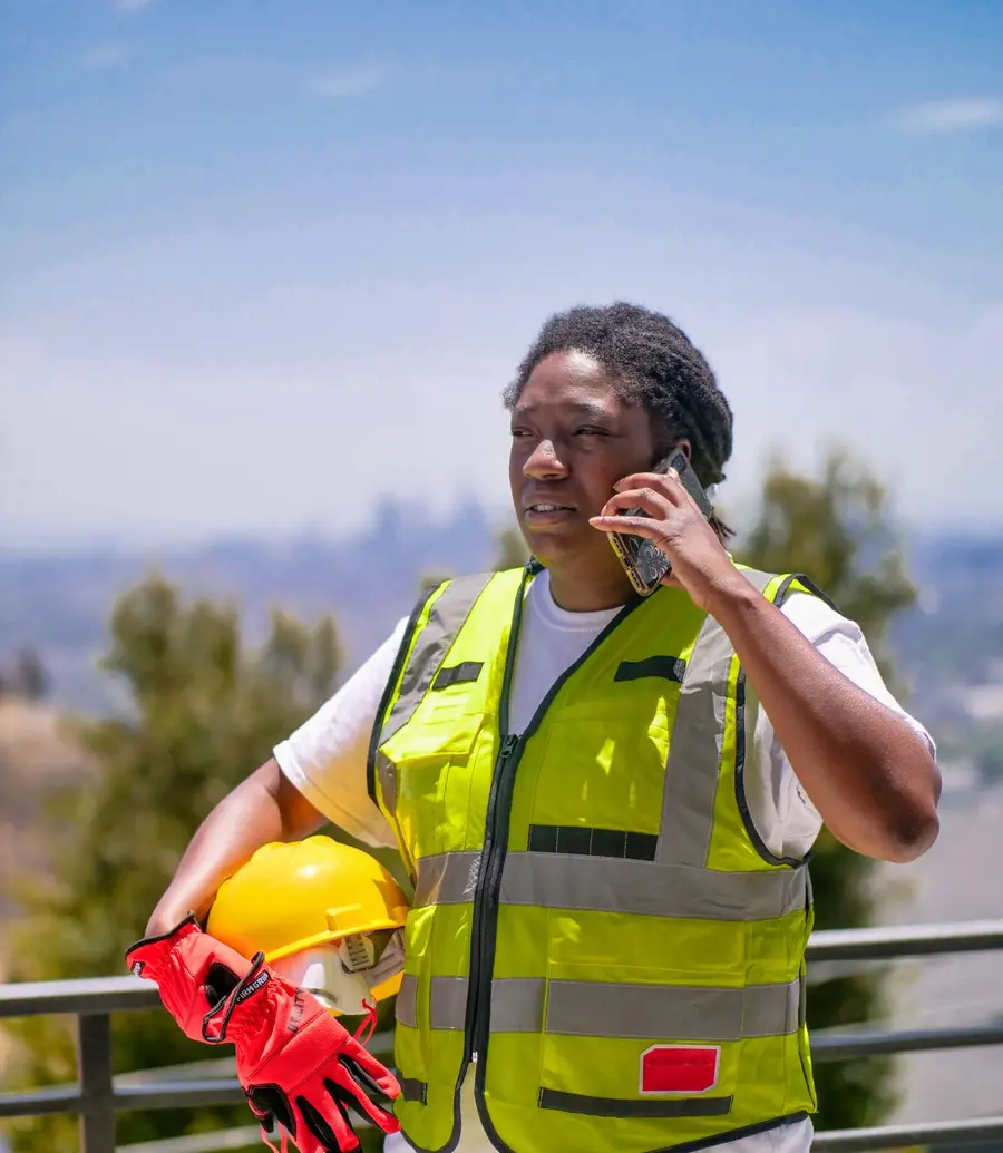 Gutter contractor in safety gear taking a call on his phone outdoors