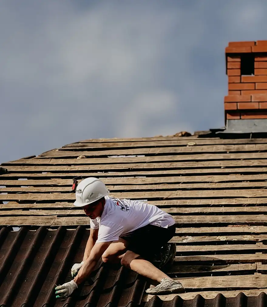 Contractor installing roofing along the edge of a sloped roof