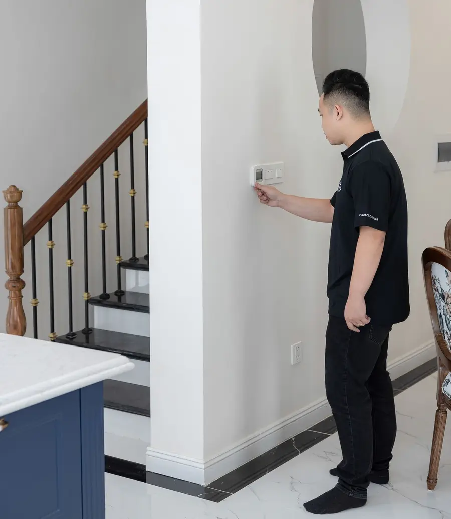 Person adjusting a wall thermostat in a modern home
