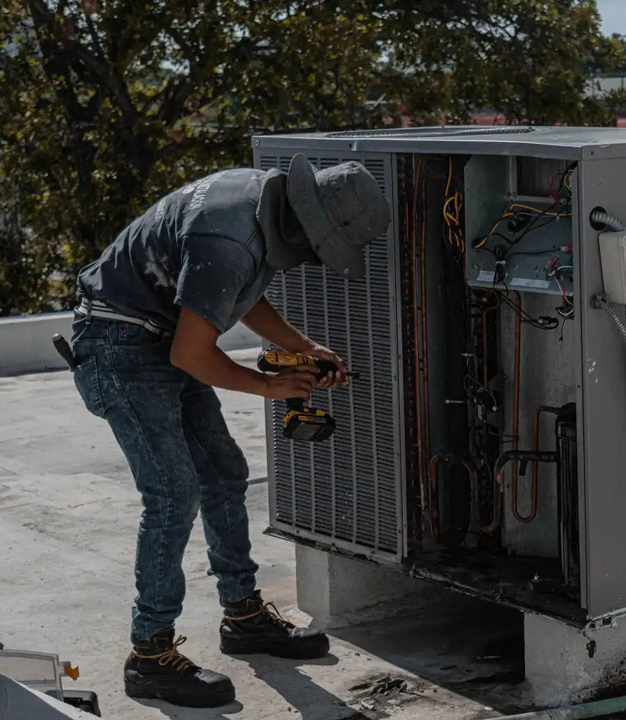 HVAC technician on a rooftop servicing an outdoor air conditioning unit