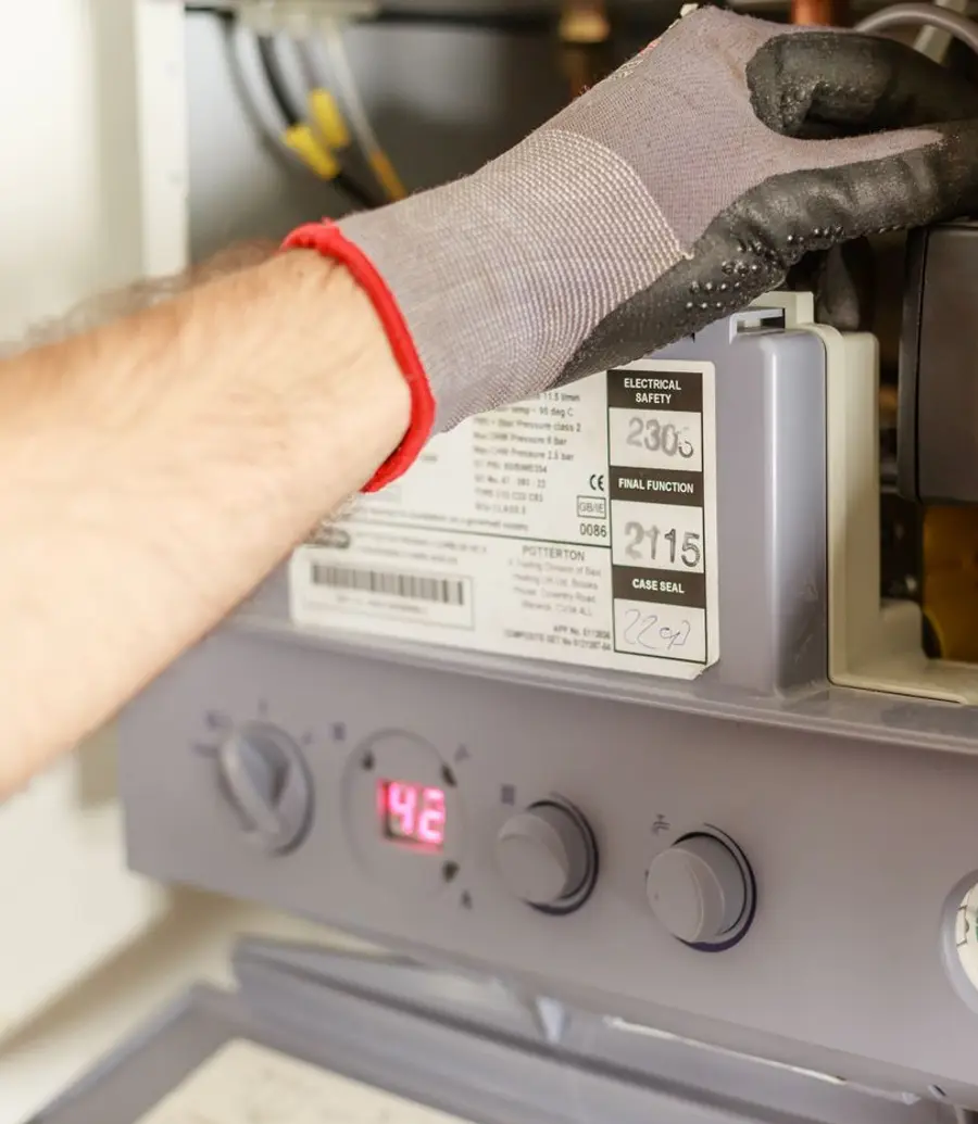 Close-up of hands servicing a boiler system with a pressure gauge