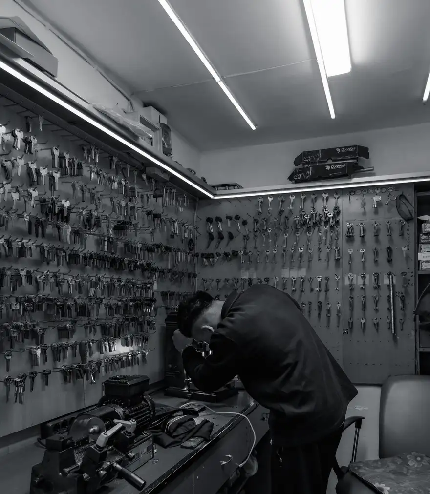 Locksmith working at a bench in a dimly lit shop at night