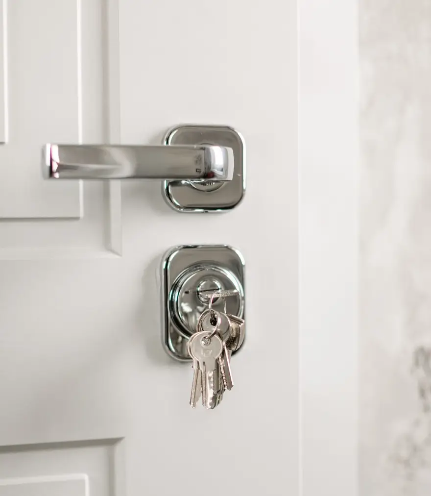 Keys hanging from the lock of a bright white residential door