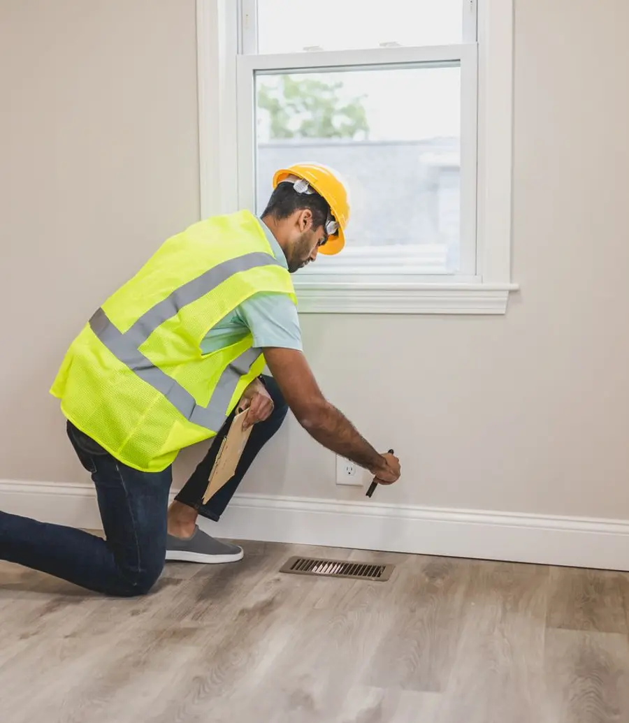 Inspector in safety gear checking a room corner for mold