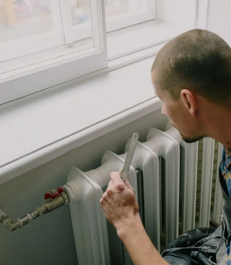 Plumber inspecting a home radiator during a daytime visit