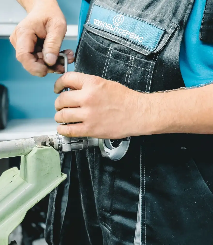 Plumber in a blue uniform tightening a pipe fitting with a wrench