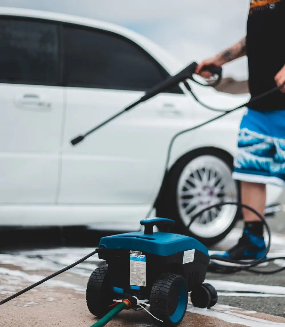 Pressure-washer unit on a driveway with an operator holding the wand