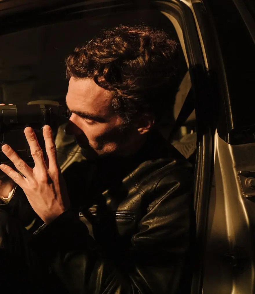 Private investigator filming with a camcorder from inside a car at night