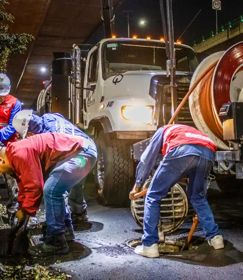 Sewer crew cleaning a drain line with machinery at night
