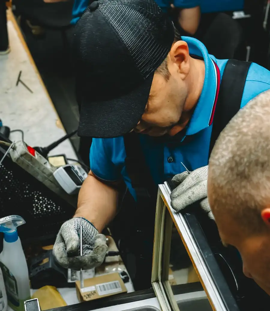 Two appliance technicians servicing an open chest freezer