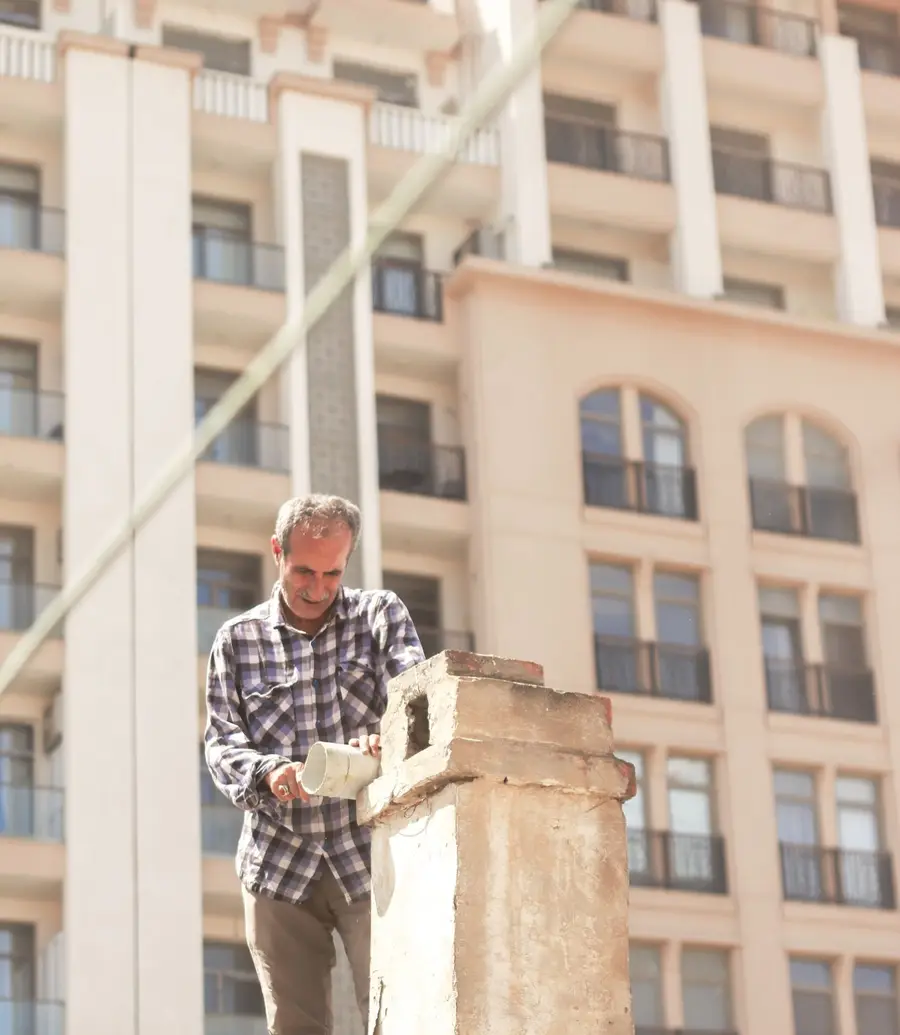 Technician repairing chimney brickwork on a rooftop during the day