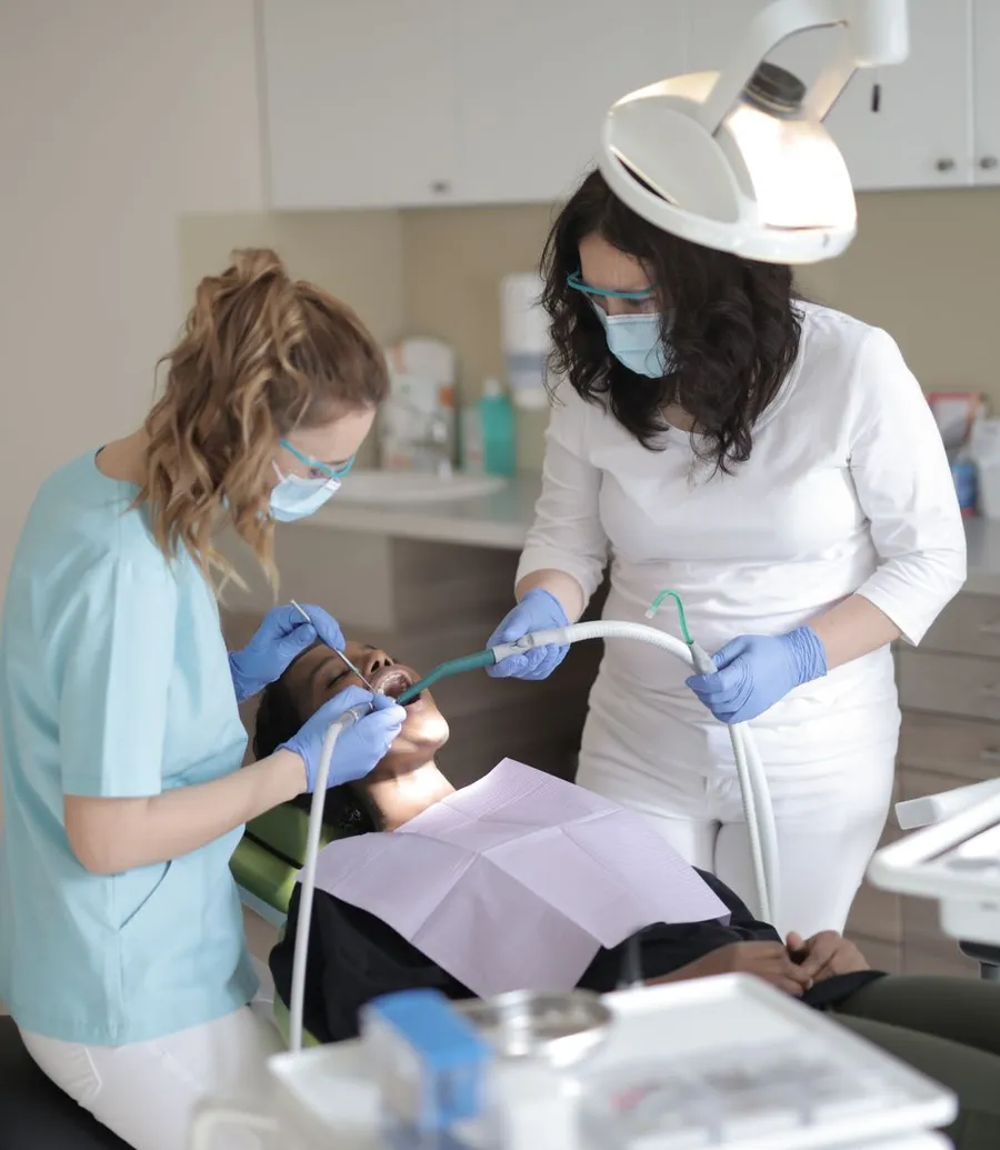 Two clinicians treating a patient in a dental chair
