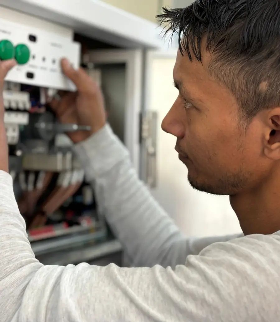 Electrician working on a control panel during a daytime visit