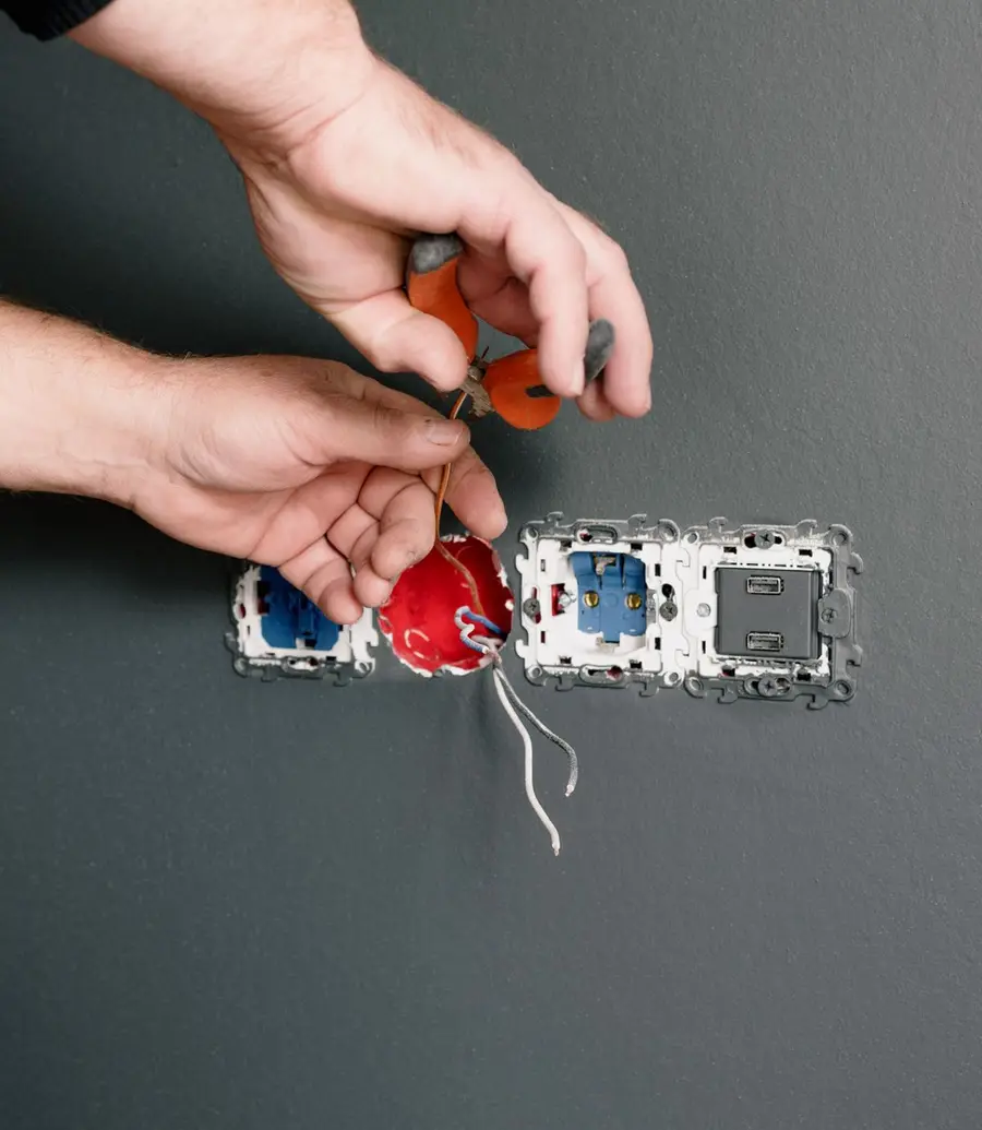 Close-up of hands wiring electrical outlets on a wall