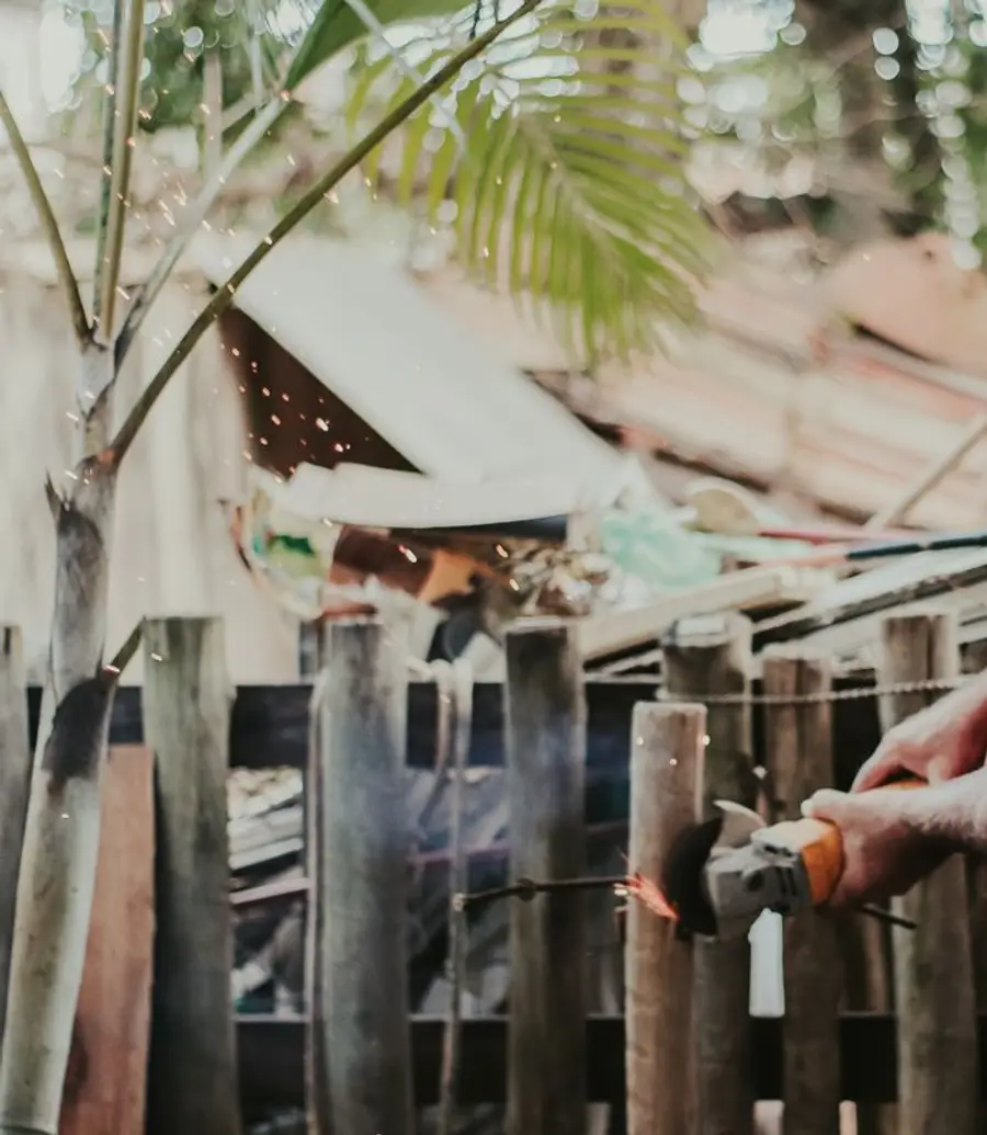 Contractor grinding a timber fence rail with sparks flying