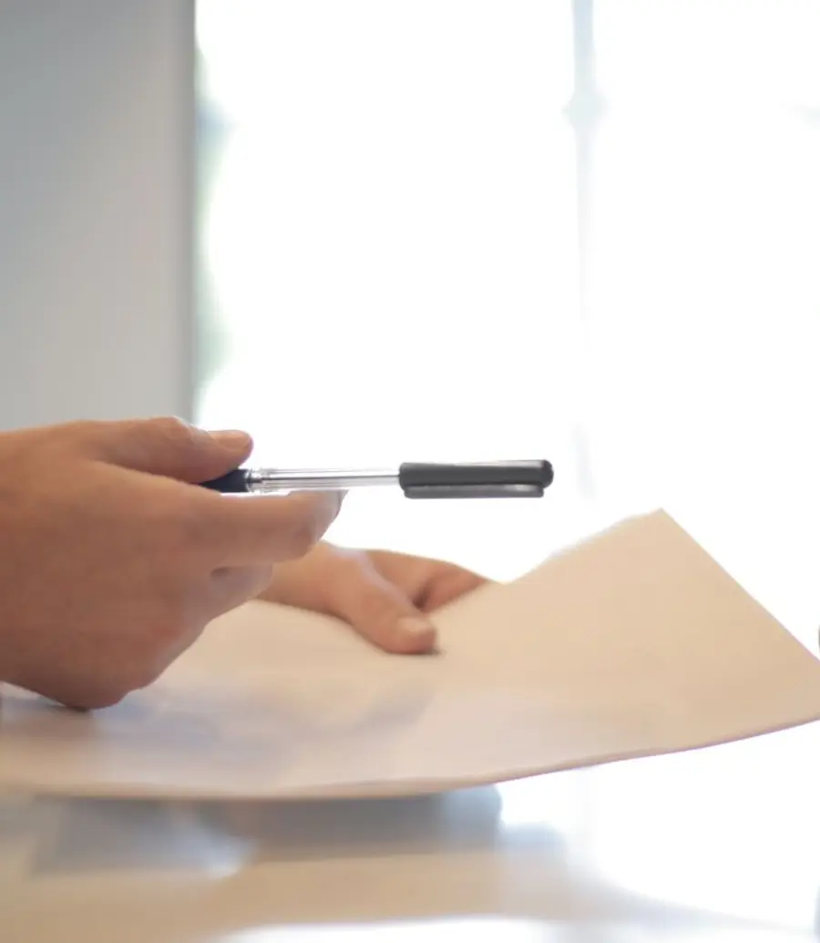 A pen offered over a document on a desk