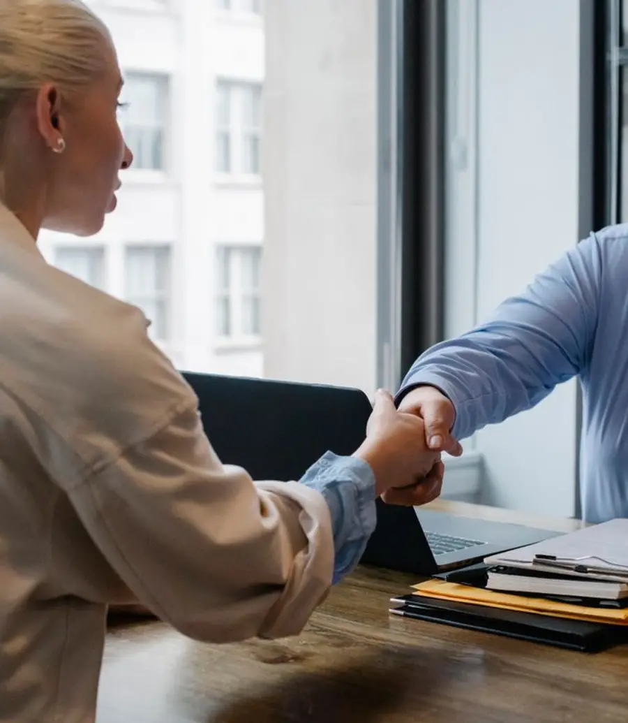 A financial advisor and a client shaking hands across a desk