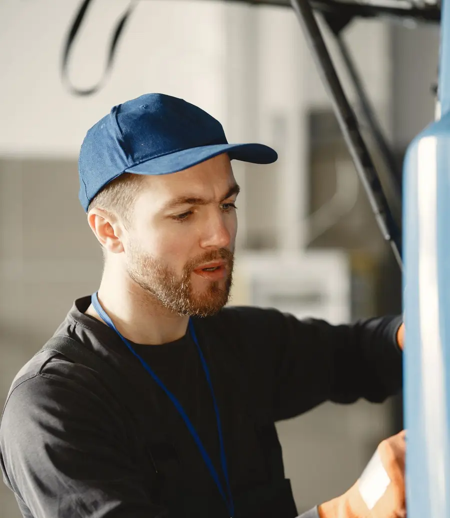 Garage door technician in a blue cap and work gloves servicing a door