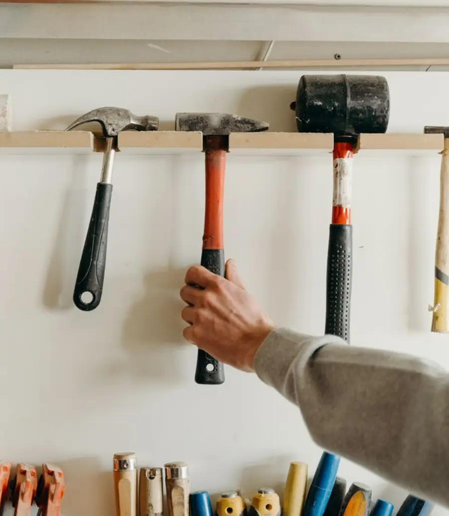 Hand reaching for a tool on a workshop wall rack