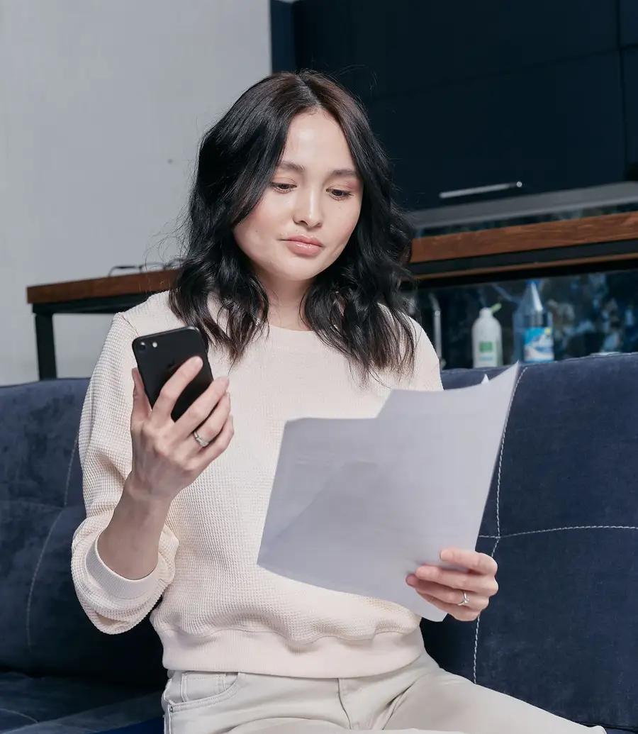 Resident reviewing a bill at her kitchen table with a phone in hand