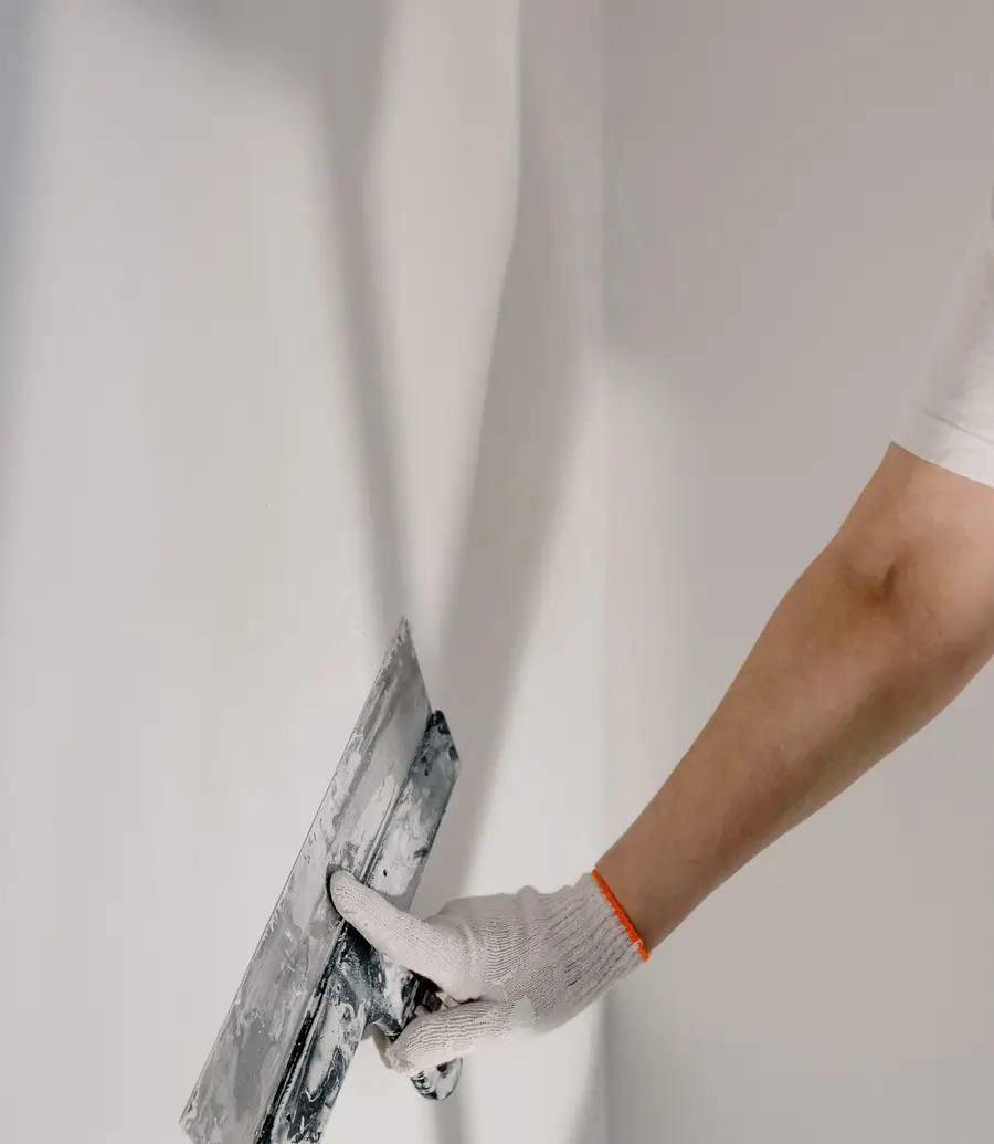 Gloved hand smoothing a wall with a plastering trowel