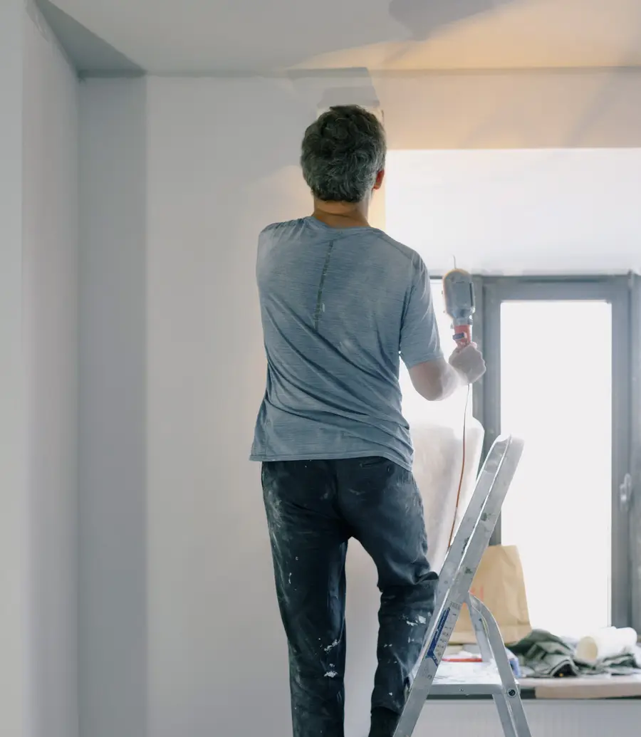 Handyman on a ladder working on an interior renovation