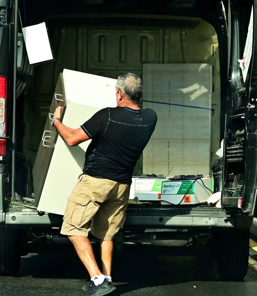 A worker unloading furniture from the back of a van