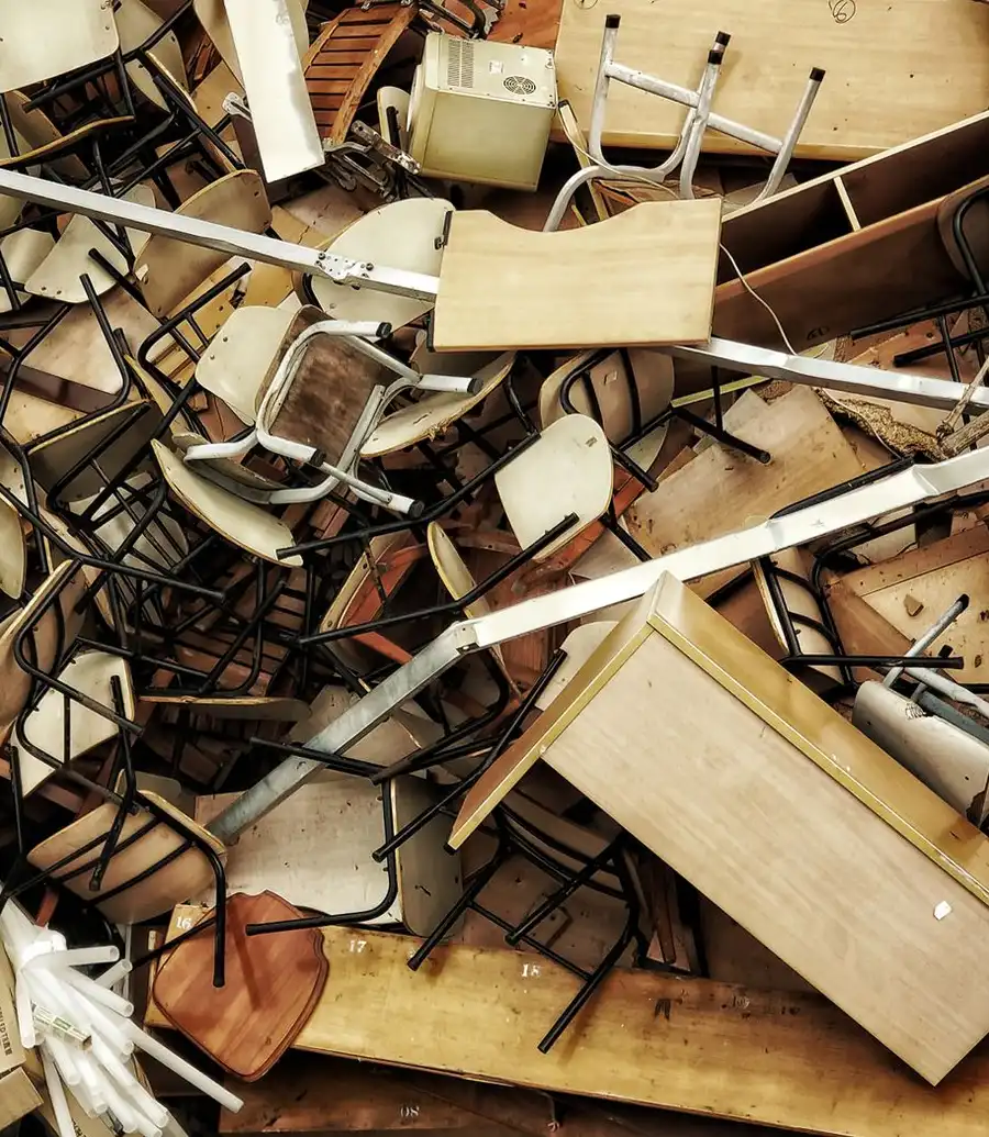 A pile of discarded wooden furniture and chairs ready for removal