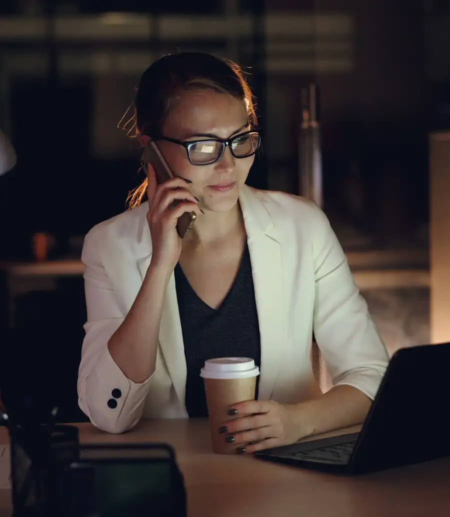 Professional taking a late-night phone call at her desk