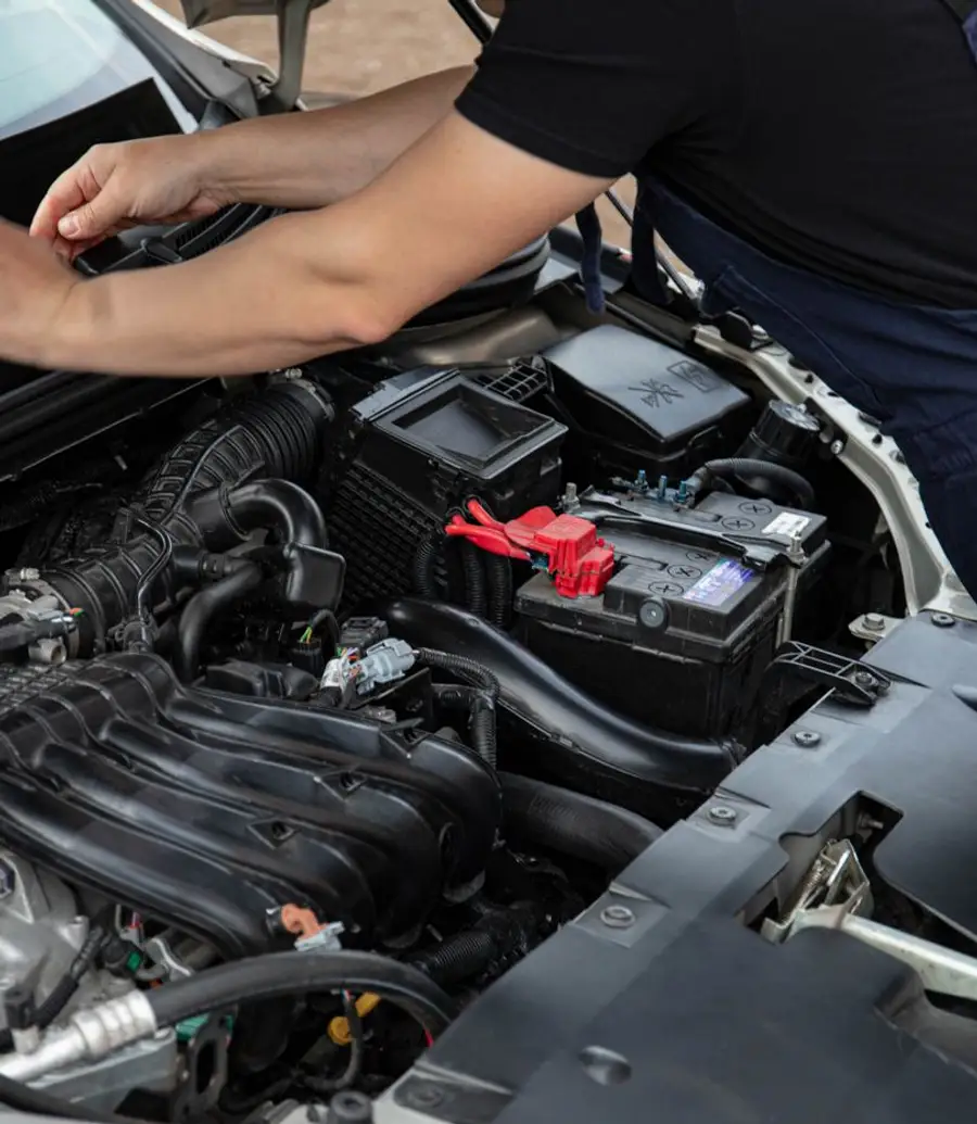 Mechanic servicing a car engine during a daytime visit