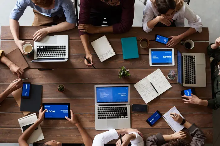 A desk covered in laptops, tablets and phones mid-project