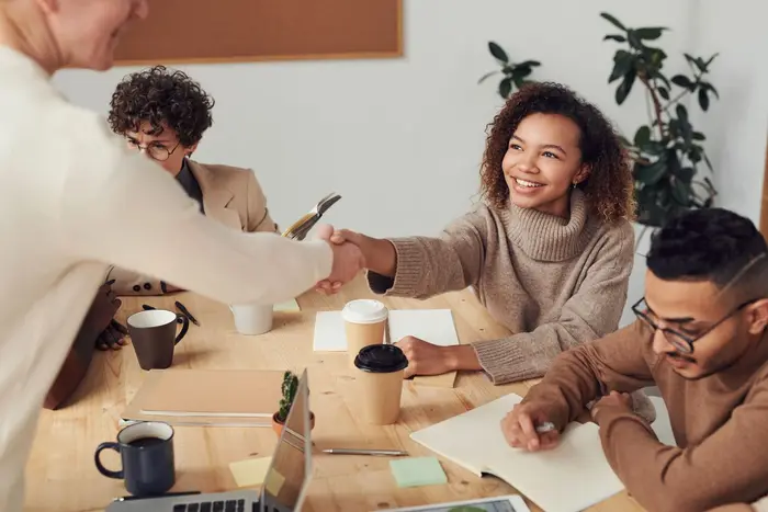Two people shaking hands across a meeting table