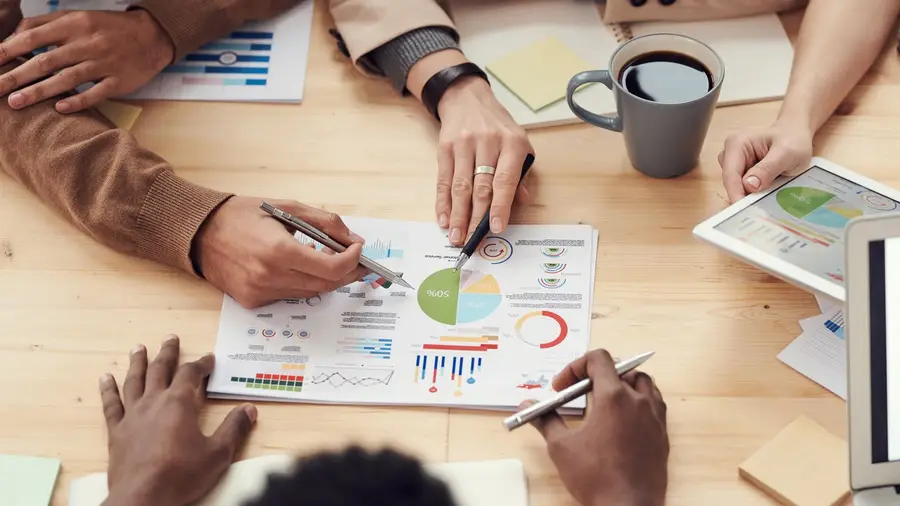 Hands reviewing revenue charts together at a desk