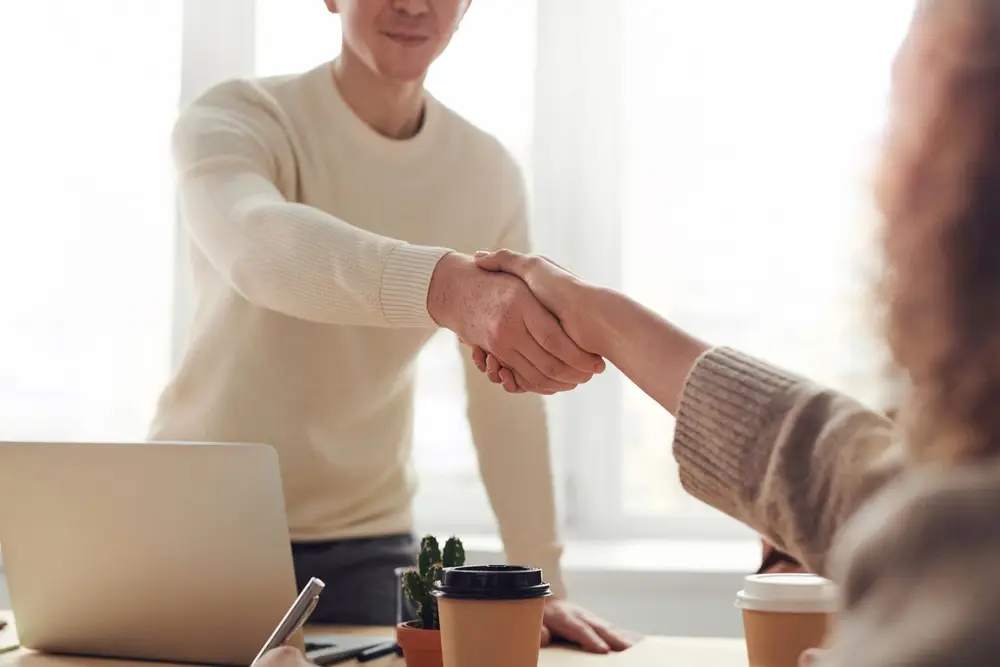 A warm handshake between two people over a desk