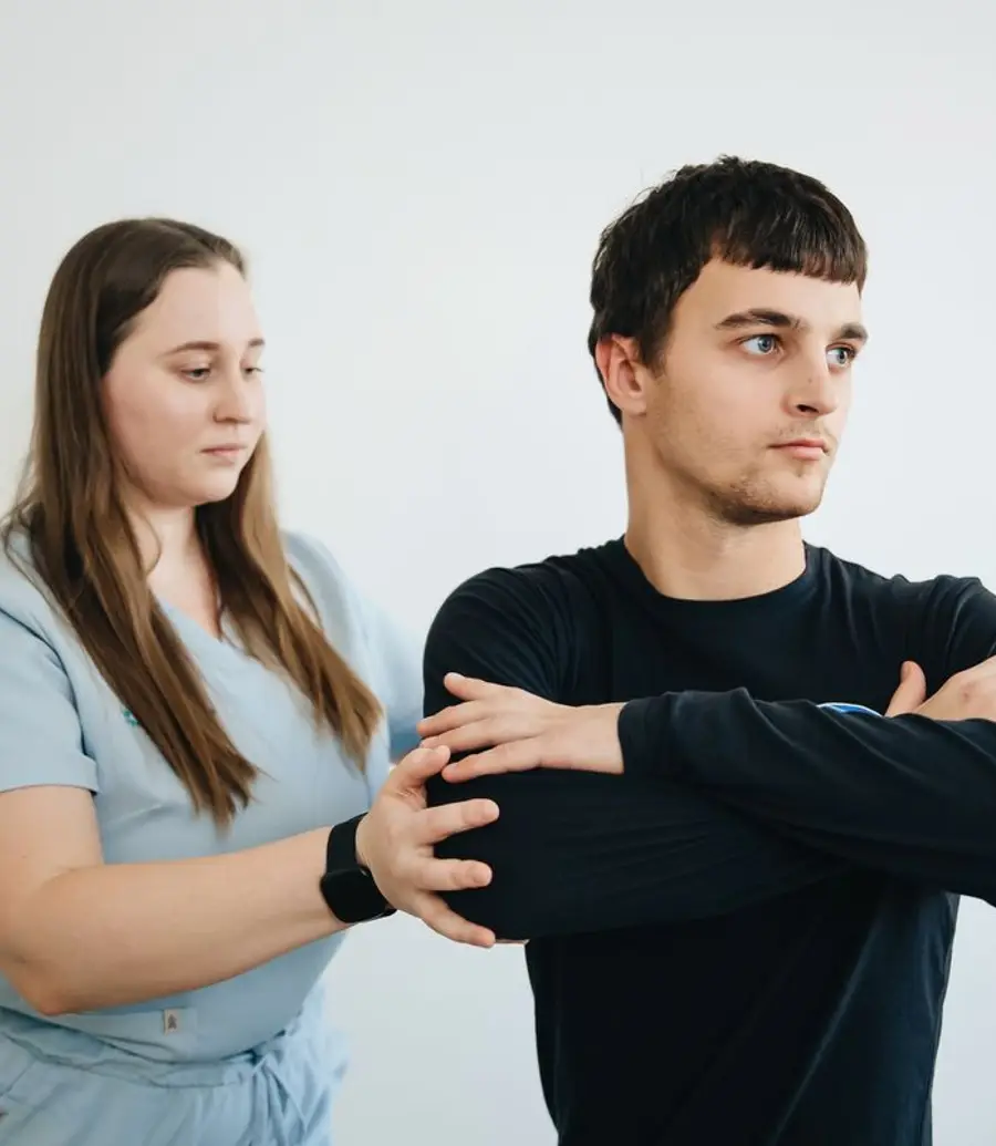 Physiotherapist supporting a patient through a standing shoulder stretch