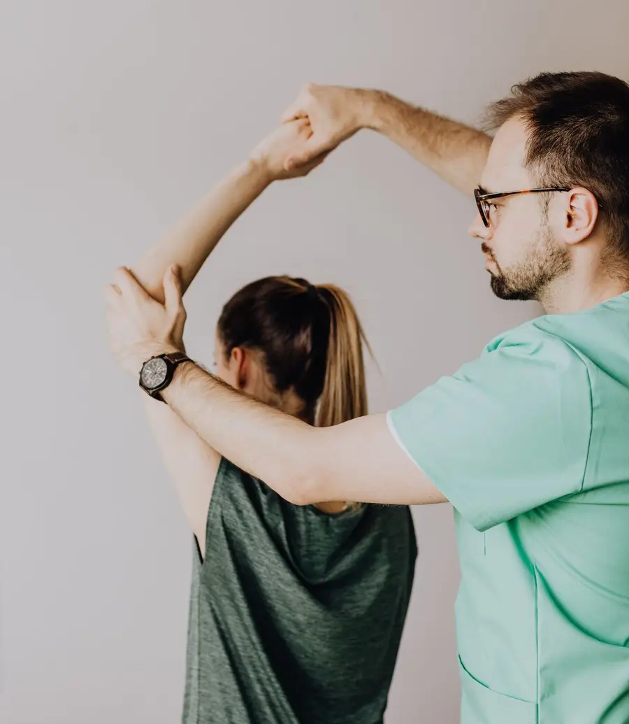 Physiotherapist assessing the shoulder range of motion of a seated patient