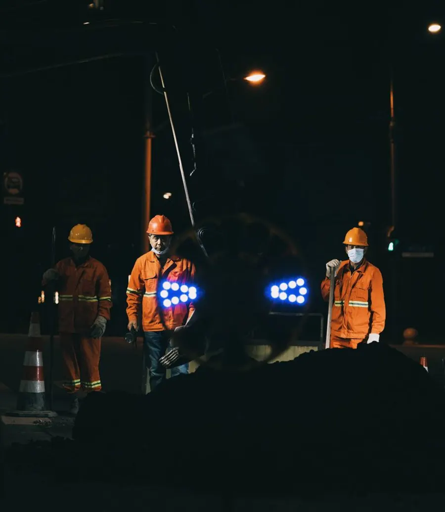 Utility crew working under floodlights at night