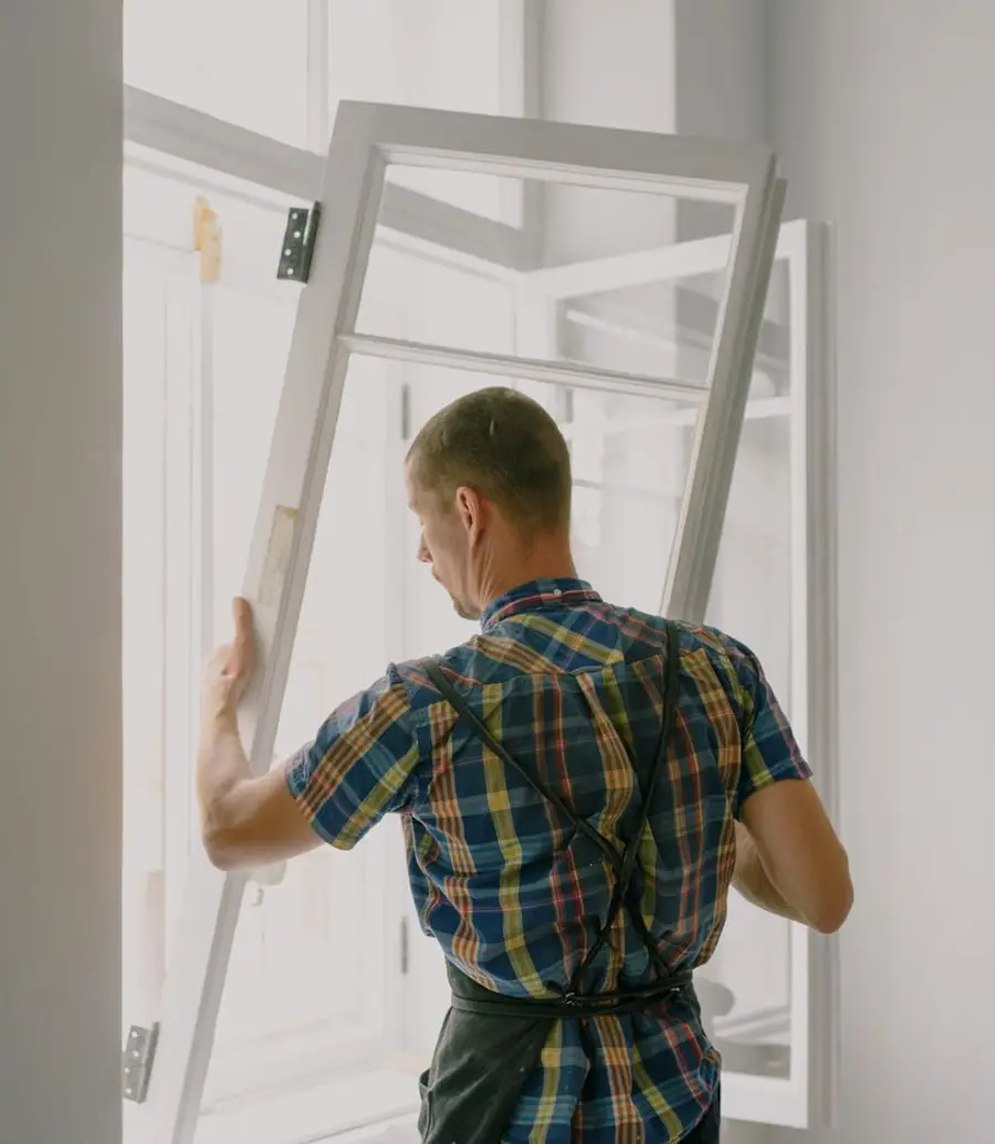 Contractor mounting a window frame near white interior walls