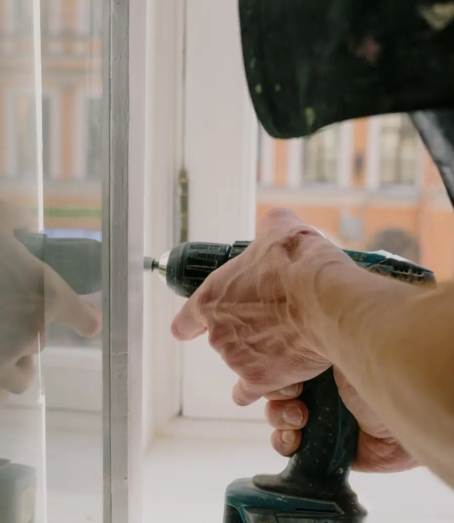 Worker assembling a white window frame in a bright room